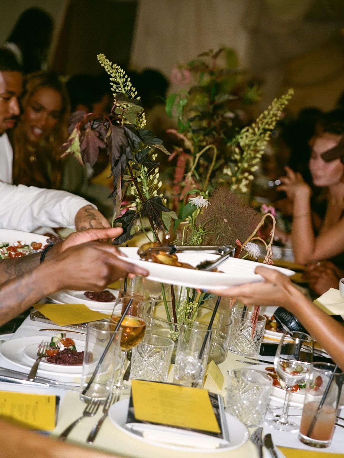 Guests sharing a candlelit family-style dinner at sunset in an open Balinese pavilion